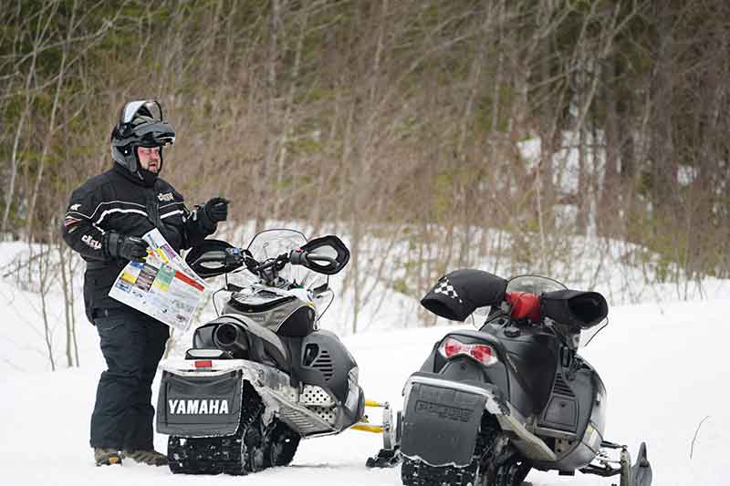 NH snowmobiler looks at trail map