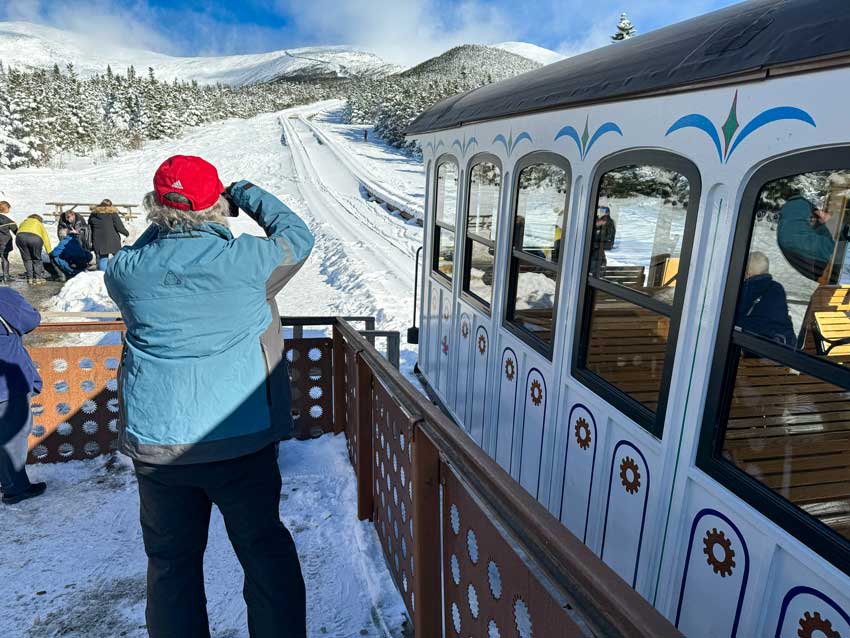 Snowmobilers takes photos of Mount Washington from the Cog Railway in the winter. Snowmobile to Mount Washington Cog railway